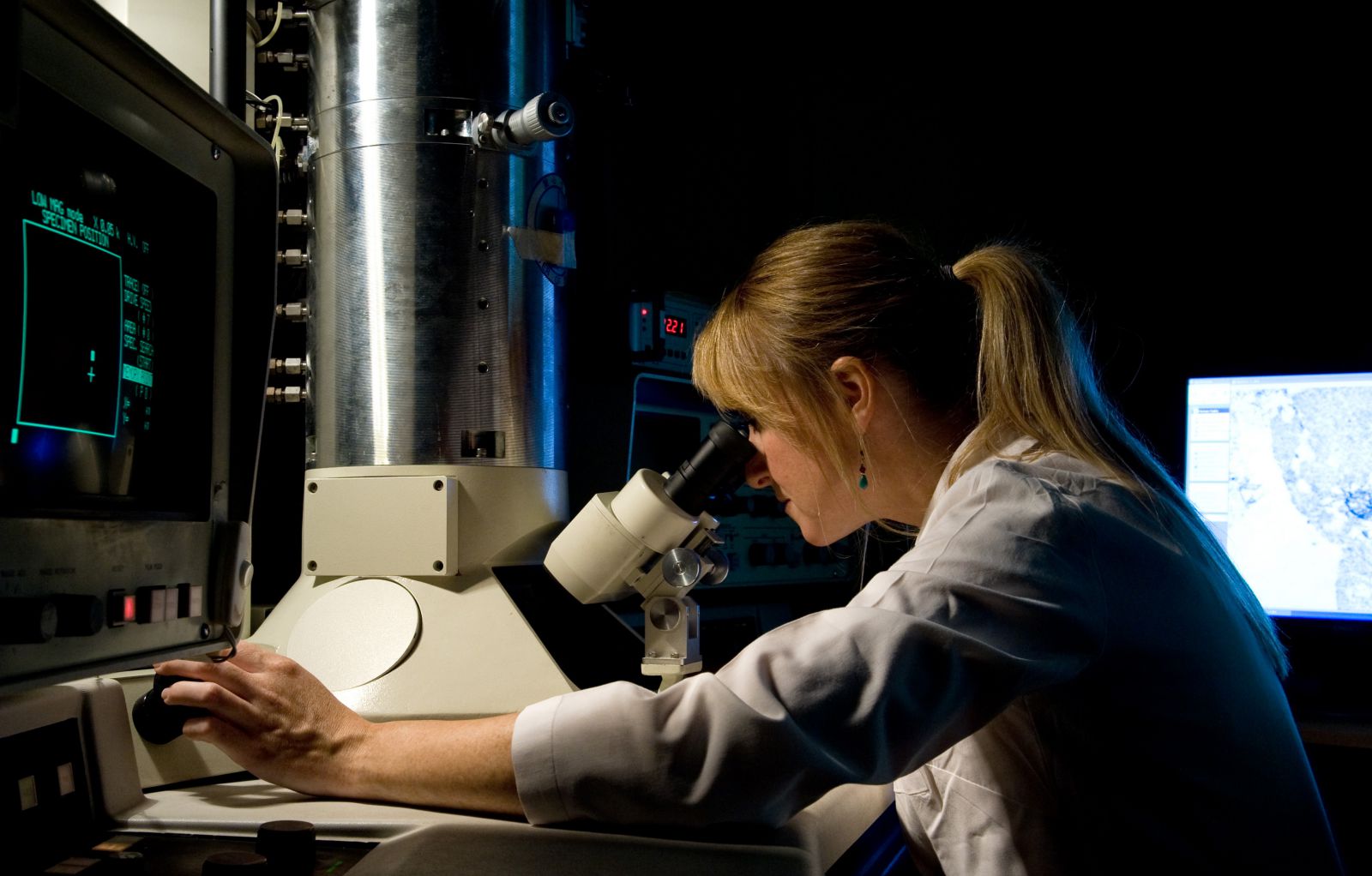 PhD student looks through a microscope in a science lab at the СƵ