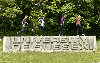 Students standing on the СƵ entrance sign