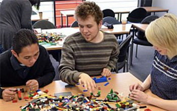Three people building with lego at the СƵ