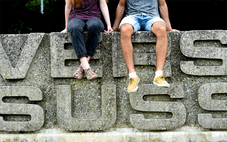 Two students sitting on the СƵ sign